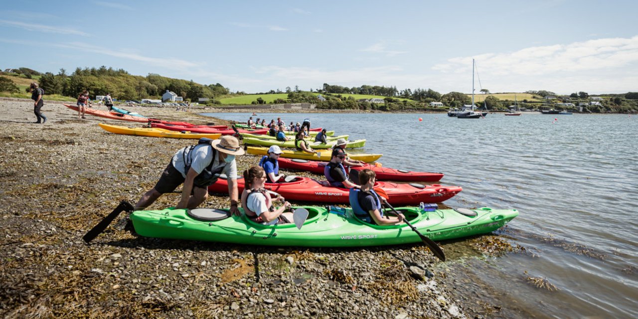 large group getting into the sea in a kayak