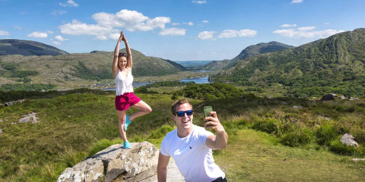 Two people taking selfie with green landscapes in background 