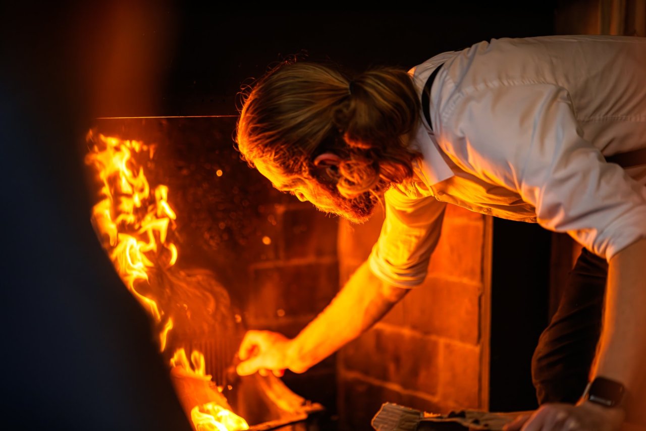 man,reaching,fire,brick,fireplace,orange,flameswhite,shirt