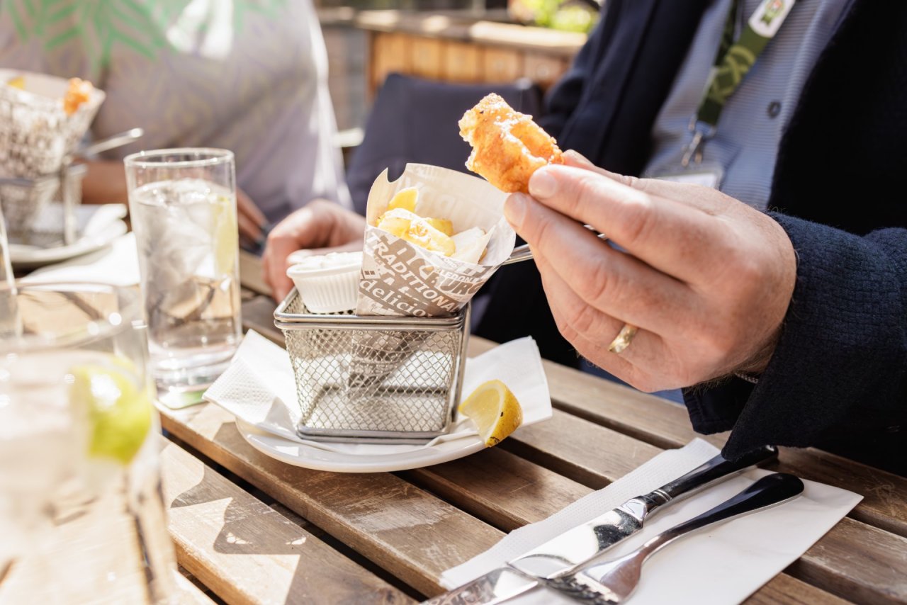 hand-gold-ring-fish-chips-wooden-table-cuttlery-outdoors