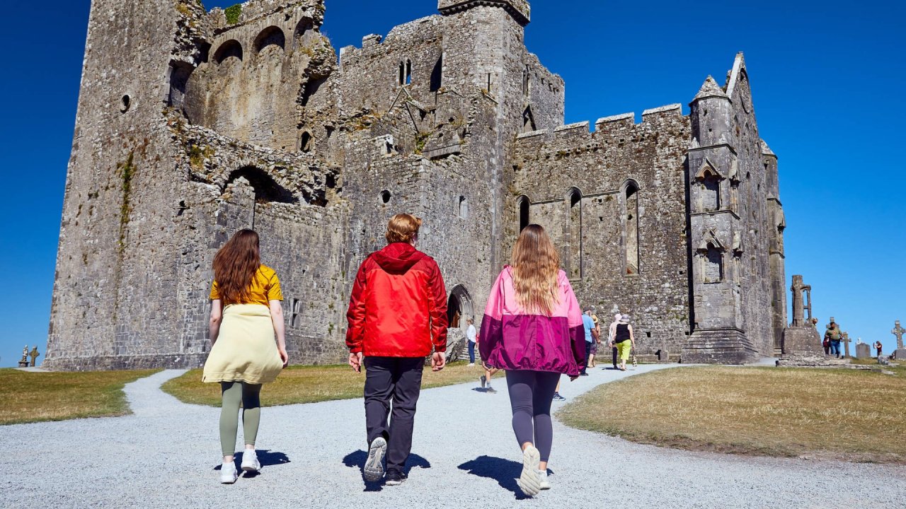 three people walking towards stone building 