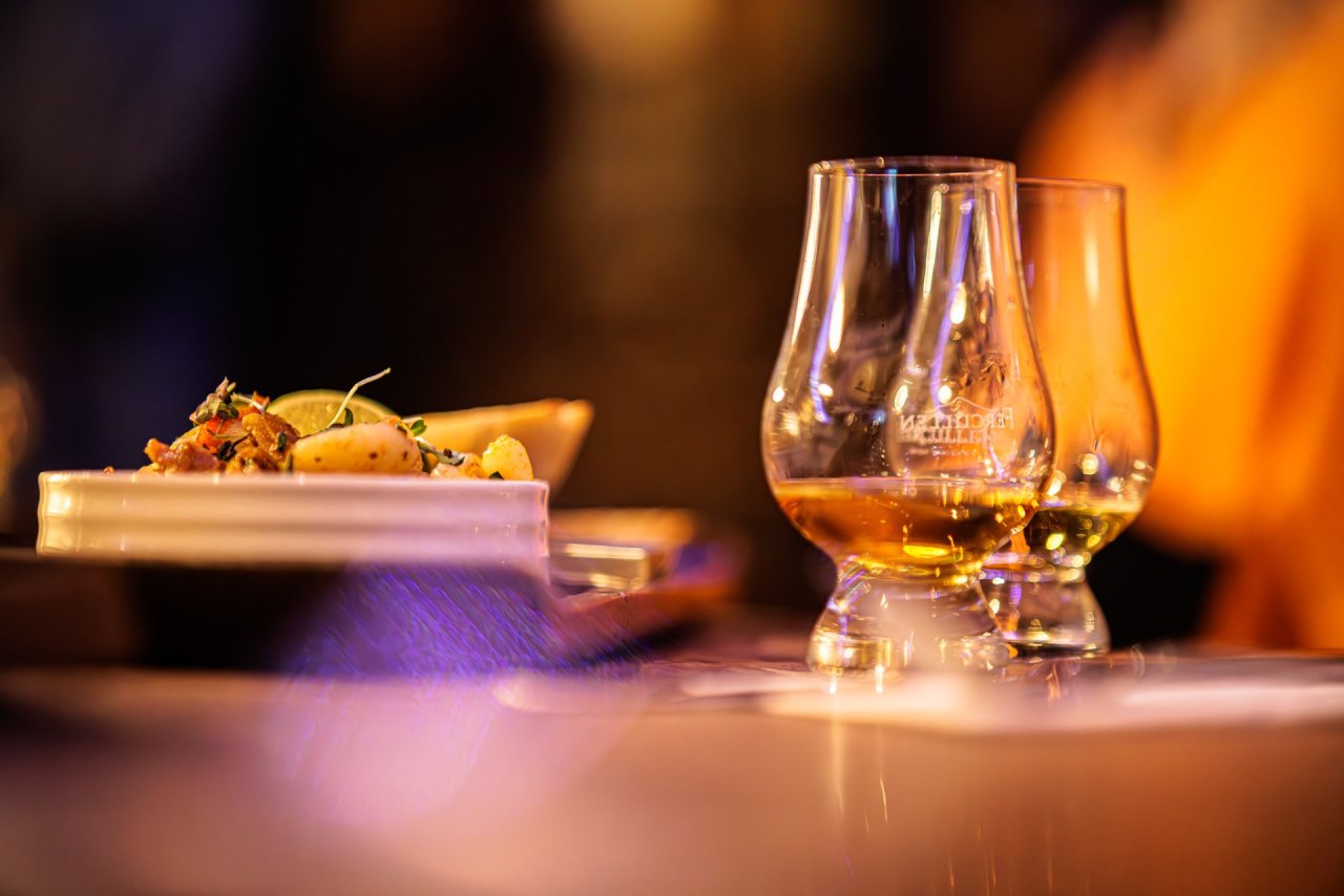 two-whiskey-glasses-orange-lighting-food-brown-table